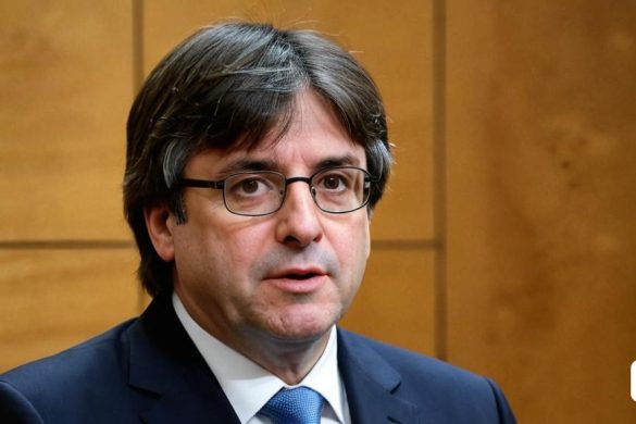 un home amb vestit i corbata parla per un micròfon davant d'una paret de fusta amb un panell de fusta darrere, Carles Delclaux Is, ignacio fernandez rios, un retrat, plasticien