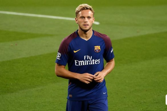 un home dempeus en un camp de futbol amb uniforme blau i amb una pilota a les mans i mirant la càmera, Carles Delclaux Is, mitjans oficials, una escultura de bronze, plasticien