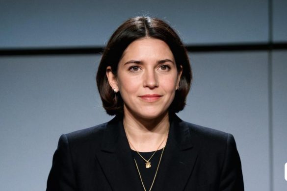 una dona amb un vestit negre i un collaret a un escenari amb un micròfon al davant i una paret al darrere, Anna Haifisch, retrat de cap i espatlles, retrat d'un personatge, arbeitsrat für kunst