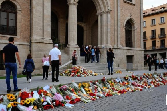 un grup de persones al voltant d'un ram de flors i flors a terra prop d'un edifici amb un munt de gent passant, Arthur Sarkissian, art nou, una foto, unilalianisme