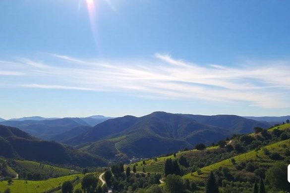 una vista panoràmica d'una vall i muntanyes amb un tren a les vies en primer pla i un cel blau amb núvols blancs, Ada Hill Walker, cel blau, una pintura mat, incoherents