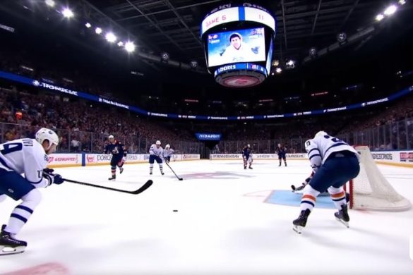 La escena captura un momento intenso del juego de playoffs de la NHL entre los Toronto Maple Leafs y los Florida Panthers. La pista está iluminada por luces superiores brillantes, lanzando un brillo vibrante en el hielo, que está marcado con los logotipos del equipo y los débiles rastros de los patines de los jugadores. En primer plano, Auston Matthews, con su icónica camiseta de Maple Leafs azules y blancos con el número '34' EMBLAZONE en la parte posterior, es de acción a mitad de acción, está terminando para un poderoso disparo de muñeca. Su expresión es de feroz determinación, con su ceño fruncido y los ojos centrados en la red. En el fondo, el portero, Sergei Bobrovsky, está en una postura de mariposa, sus almohadillas se extienden de par en par, lista para bloquear el inminente disparo. La multitud es un mar de azul y blanco, con fanáticos en pie, algunos sosteniendo señales y otros que capturan el momento en sus teléfonos. La energía en la arena es palpable, con tensión colgando en el aire mientras tod